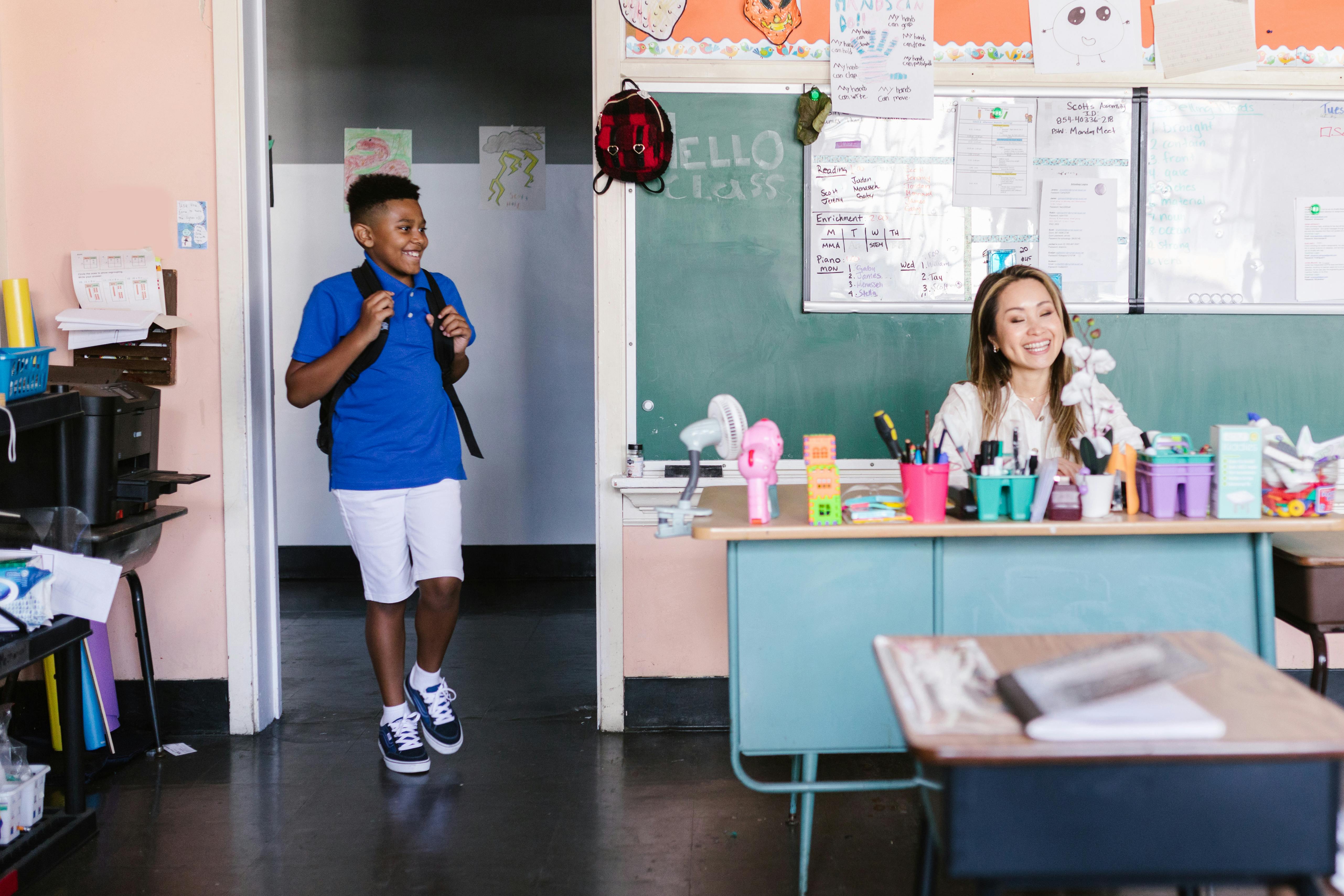 Happy child entering classroom with backpack during school holiday club and HAF activities
